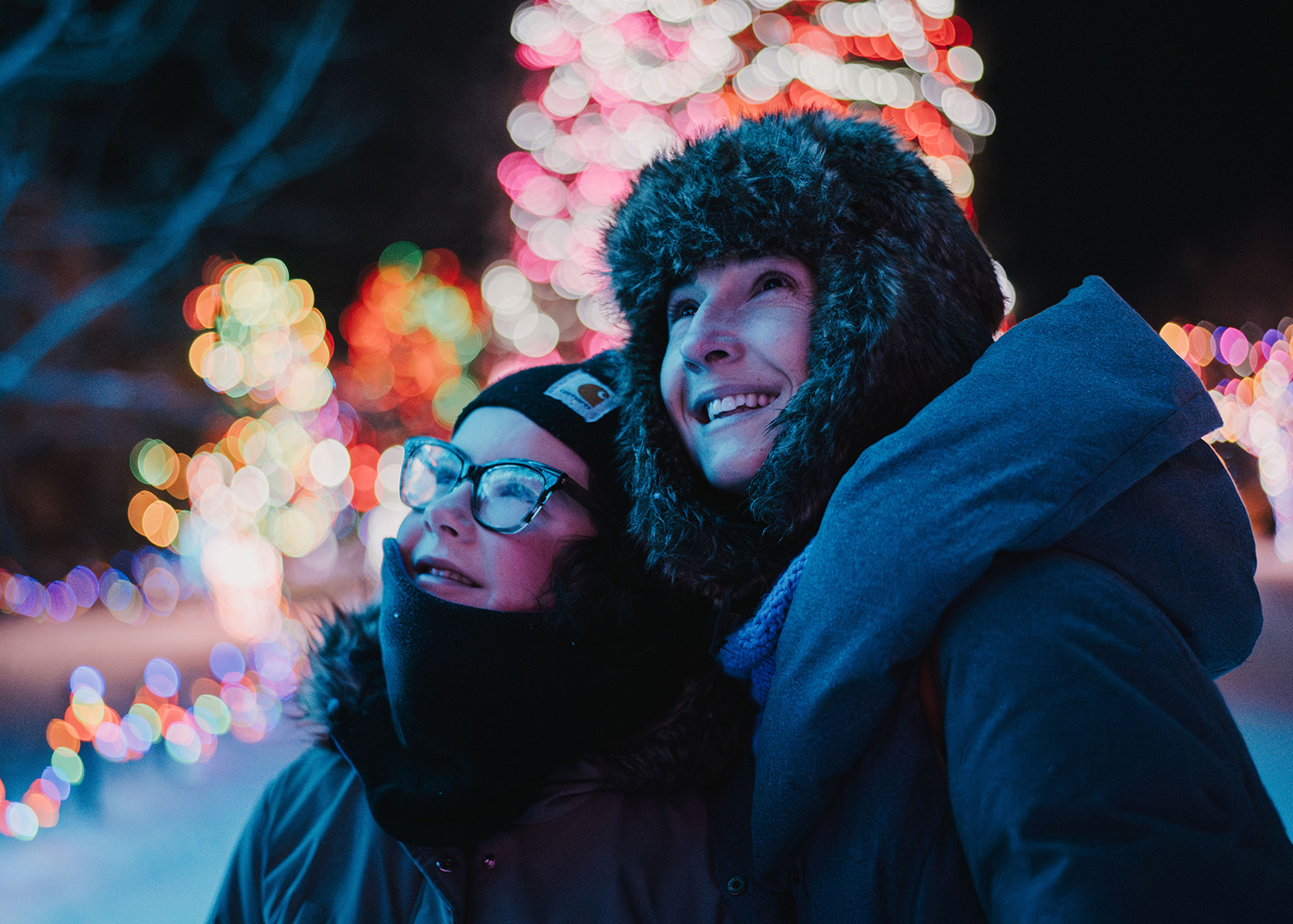 A mom and child look up at holiday lights